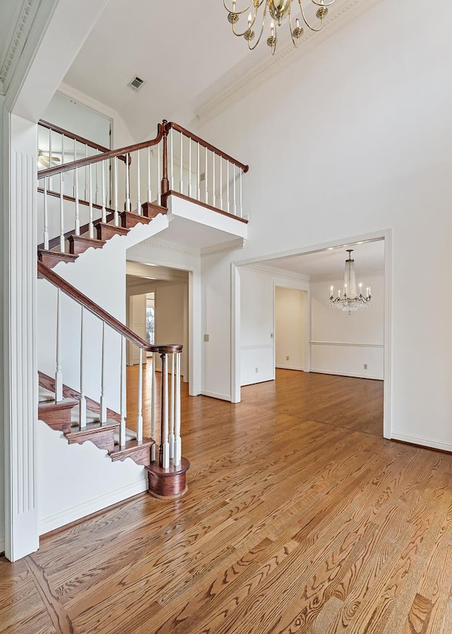 interior space featuring a chandelier, stairway, wood finished floors, and a towering ceiling