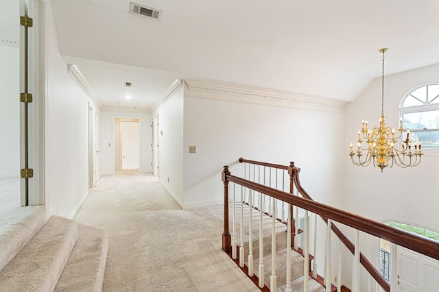 corridor with light colored carpet, an upstairs landing, visible vents, ornamental molding, and attic access