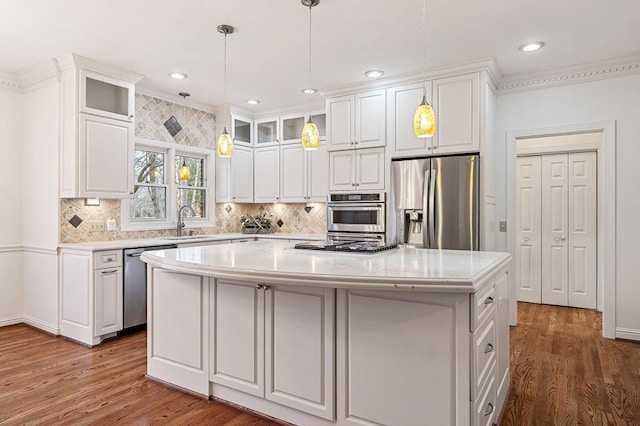 kitchen with glass insert cabinets, a center island, stainless steel appliances, white cabinetry, and a sink