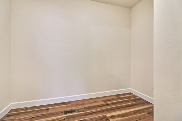 spare room featuring visible vents, baseboards, and dark wood-style flooring