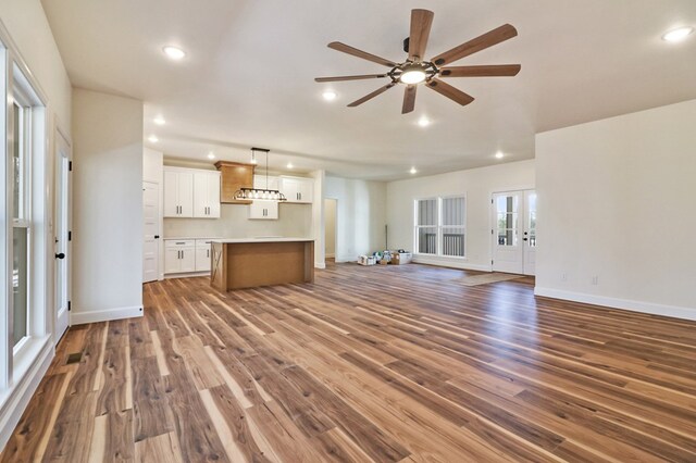 unfurnished living room featuring a ceiling fan, recessed lighting, baseboards, and wood finished floors