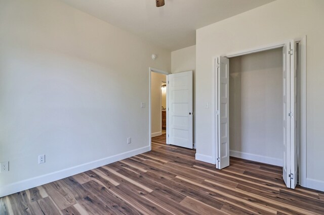 unfurnished bedroom featuring dark wood finished floors, a ceiling fan, and baseboards