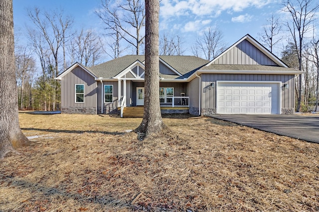 view of front facade featuring aphalt driveway, an attached garage, stone siding, roof with shingles, and board and batten siding