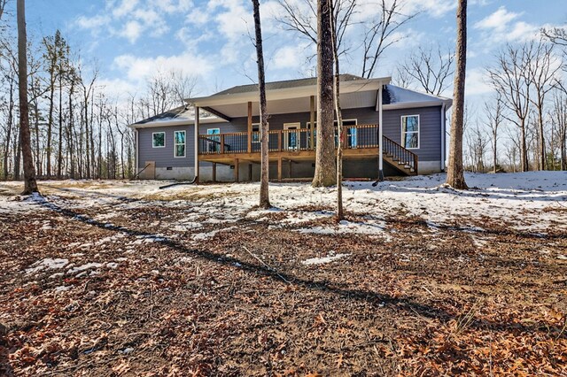 snow covered back of property featuring covered porch and crawl space