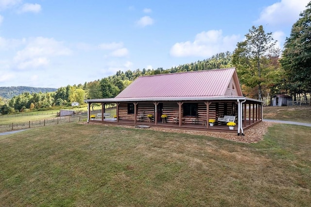 view of front of home with a front lawn, an outbuilding, metal roof, and a forest view