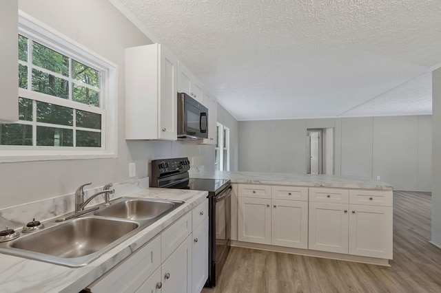 kitchen featuring a peninsula, black appliances, a sink, and white cabinets