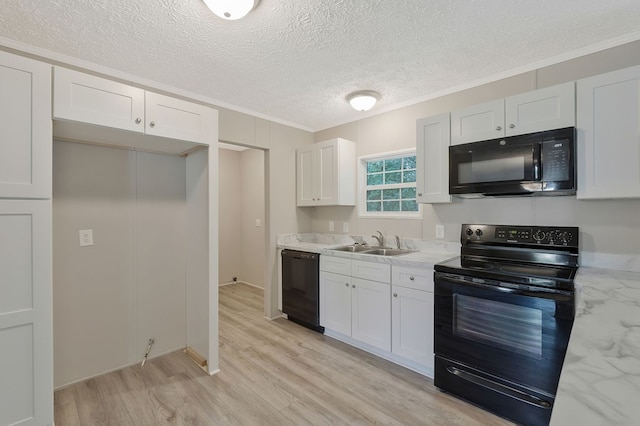 kitchen featuring light stone counters, light wood-style floors, white cabinetry, a sink, and black appliances