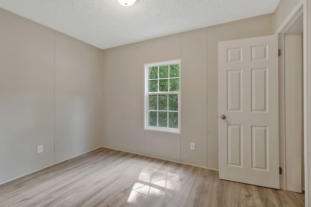 spare room featuring a textured ceiling and light wood finished floors