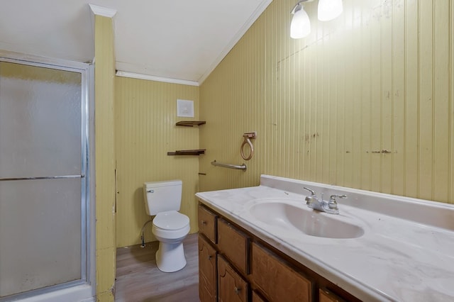 bathroom with toilet, wood finished floors, crown molding, vanity, and a shower stall