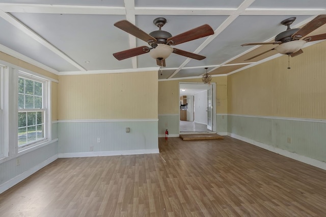 empty room featuring ceiling fan, coffered ceiling, wood finished floors, and wainscoting