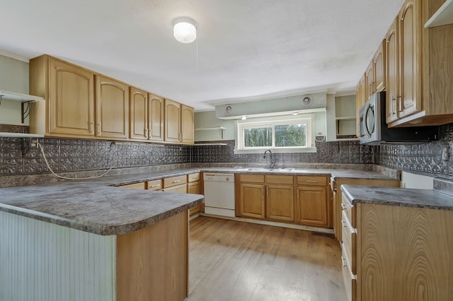 kitchen featuring dark countertops, a sink, white dishwasher, open shelves, and backsplash