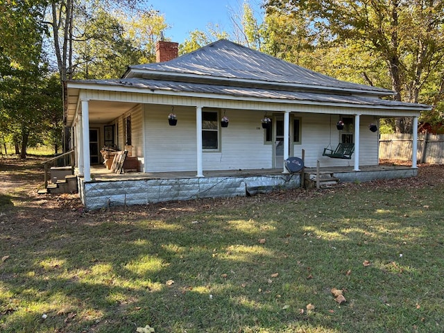 farmhouse inspired home featuring a porch, a front yard, metal roof, and a chimney