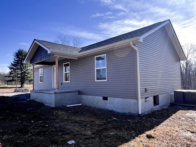 view of property exterior featuring crawl space, central AC, and roof with shingles