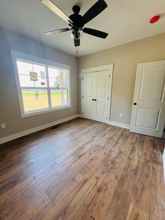 unfurnished bedroom featuring light wood finished floors, visible vents, baseboards, and a ceiling fan