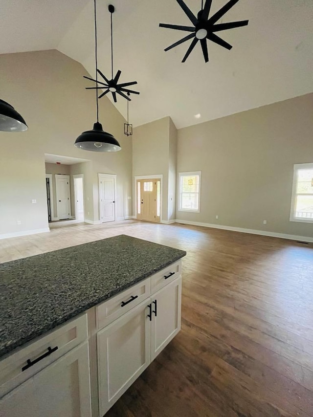 kitchen featuring open floor plan, dark stone countertops, white cabinetry, and a healthy amount of sunlight