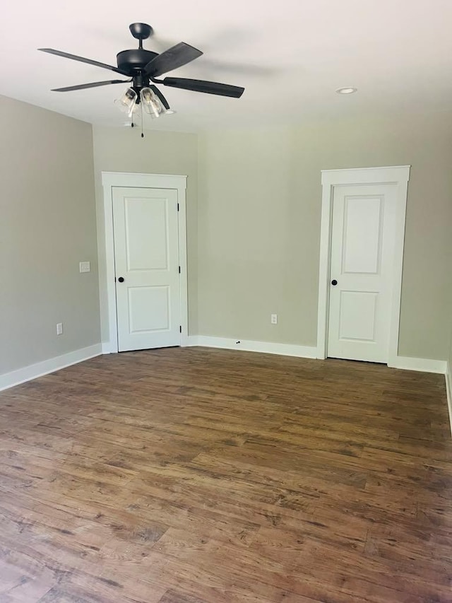 empty room with dark wood finished floors, baseboards, and ceiling fan