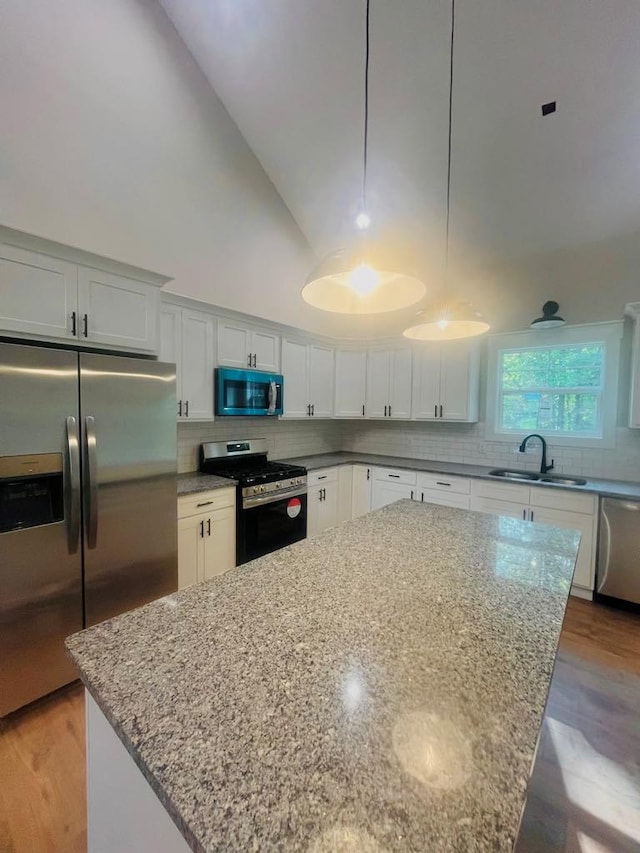 kitchen with stainless steel appliances, pendant lighting, white cabinets, and a kitchen island