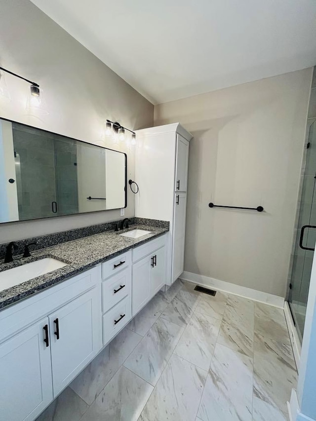 full bath featuring marble finish floor, a stall shower, a sink, and baseboards