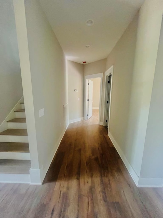 hall featuring stairs, baseboards, and wood finished floors