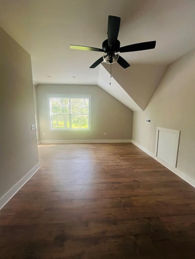 bonus room featuring vaulted ceiling, dark wood-type flooring, a ceiling fan, and baseboards