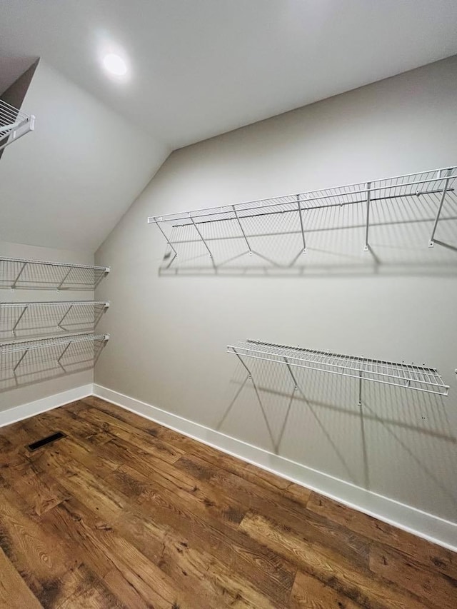 spacious closet featuring visible vents, vaulted ceiling, and wood finished floors