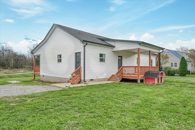 rear view of property with entry steps, a shingled roof, crawl space, and a lawn