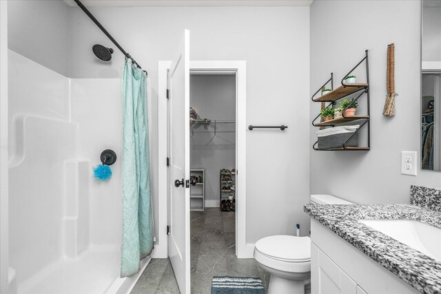 bathroom with baseboards, toilet, a spacious closet, vanity, and a shower stall