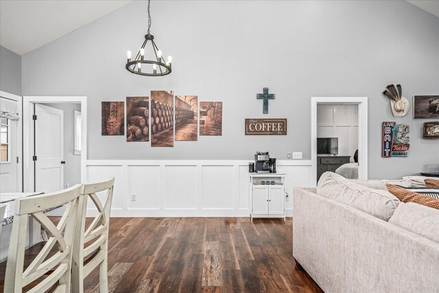 interior space with a wainscoted wall, a decorative wall, dark wood-type flooring, vaulted ceiling, and a chandelier