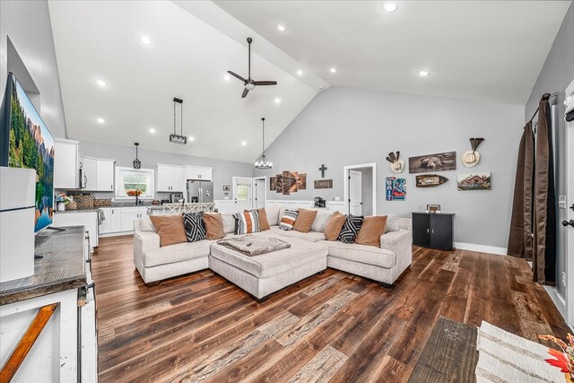 living area with dark wood-style floors, high vaulted ceiling, a ceiling fan, and baseboards