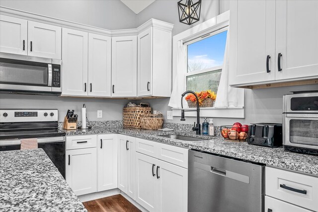 kitchen featuring light stone countertops, white cabinetry, appliances with stainless steel finishes, and a sink