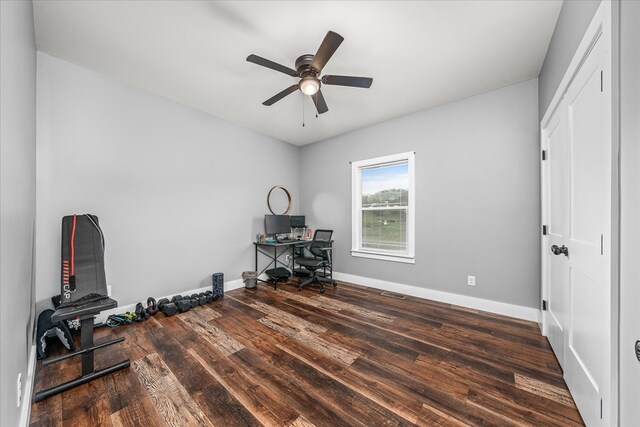 home office featuring dark wood finished floors, a ceiling fan, and baseboards