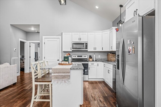 kitchen with white cabinets, a kitchen island, a kitchen breakfast bar, hanging light fixtures, and stainless steel appliances