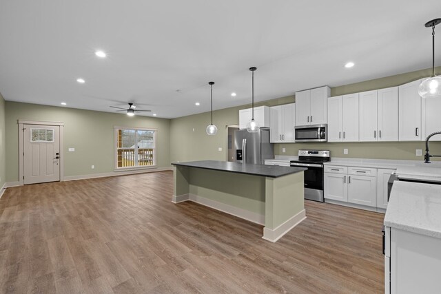 kitchen with stainless steel appliances, open floor plan, decorative light fixtures, and white cabinetry