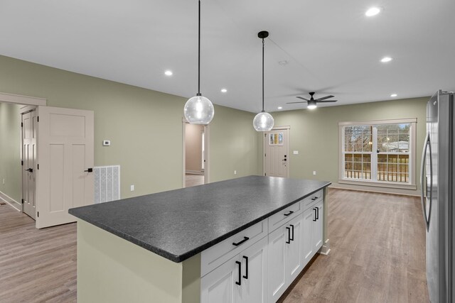 kitchen featuring white cabinets, dark countertops, a kitchen island, freestanding refrigerator, and pendant lighting