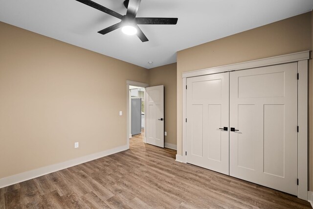 unfurnished bedroom featuring ceiling fan, a closet, light wood-type flooring, and baseboards