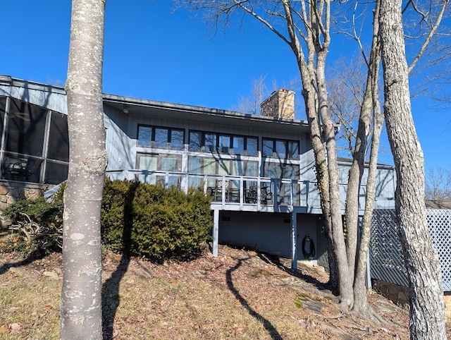 rear view of house with a sunroom and a chimney