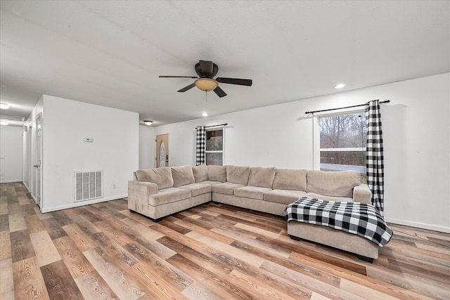 living room featuring light wood-type flooring, baseboards, and visible vents