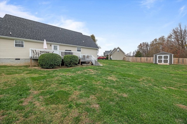 view of yard with a shed, fence, an outbuilding, and a wooden deck