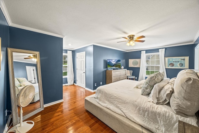 bedroom featuring a textured ceiling, multiple windows, baseboards, and wood finished floors