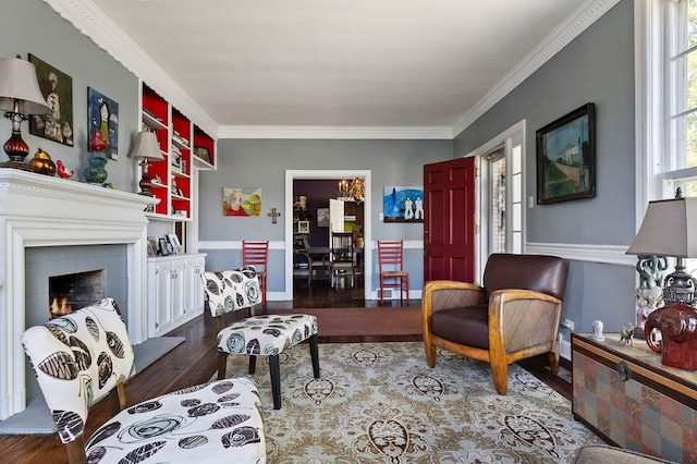 living area with a lit fireplace, wood finished floors, and crown molding