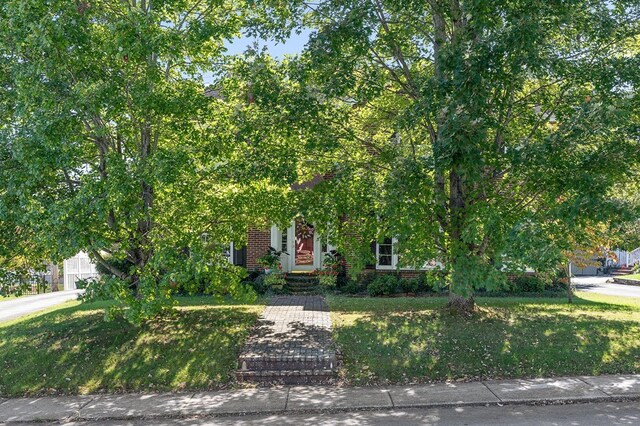 obstructed view of property featuring brick siding and a front yard