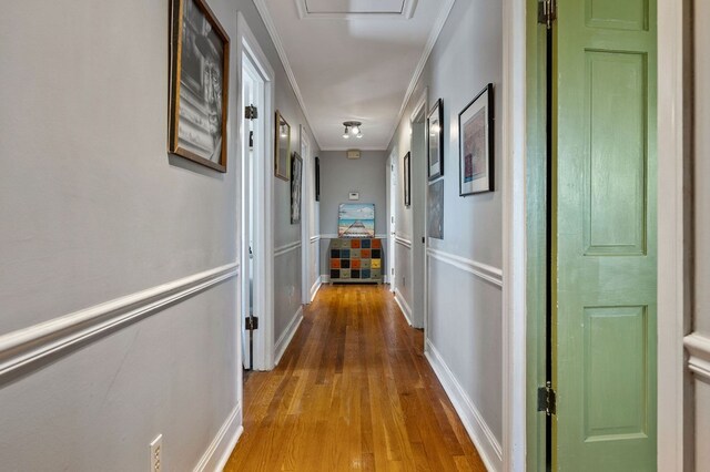 hallway featuring baseboards, crown molding, and wood finished floors