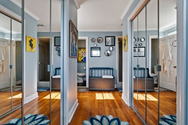 doorway with ornamental molding, wood finished floors, and baseboards