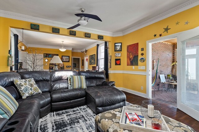 living room featuring ornamental molding, a ceiling fan, baseboards, and wood finished floors