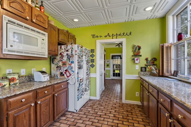 kitchen featuring an ornate ceiling, recessed lighting, light stone countertops, white appliances, and baseboards