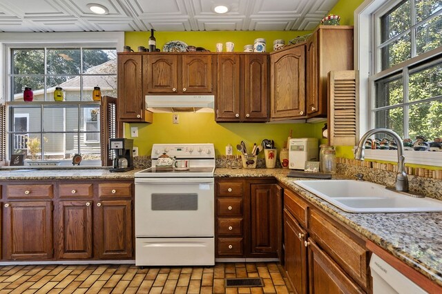 kitchen featuring an ornate ceiling, brown cabinets, a sink, white appliances, and under cabinet range hood