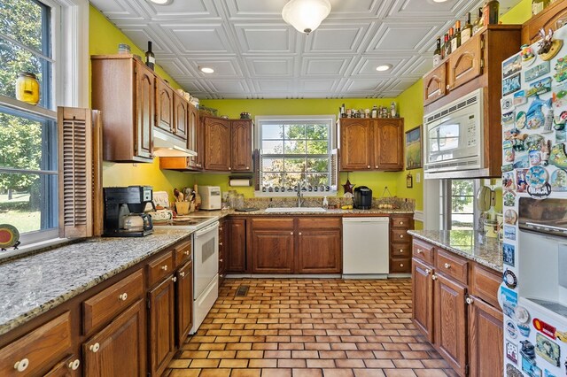 kitchen with an ornate ceiling, brown cabinets, a sink, white appliances, and under cabinet range hood