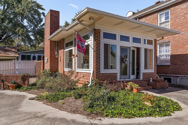 view of home's exterior featuring brick siding, fence, and a chimney