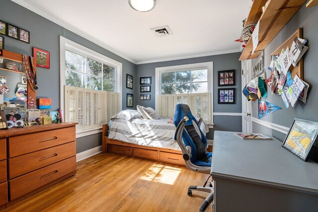 bedroom with baseboards, light wood-style flooring, visible vents, and crown molding