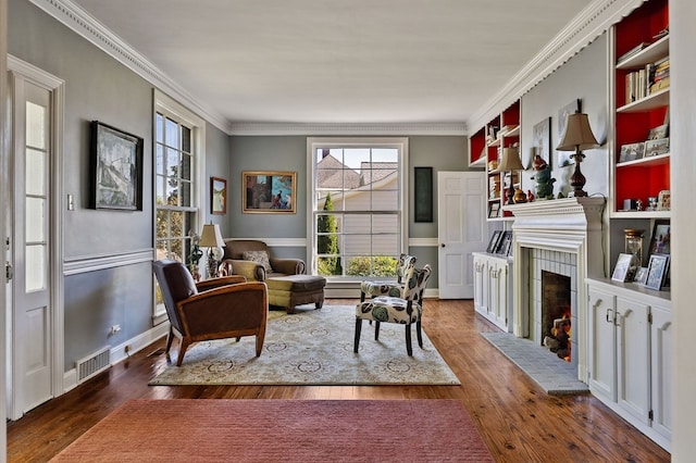 living area with a warm lit fireplace, ornamental molding, dark wood-style flooring, and visible vents